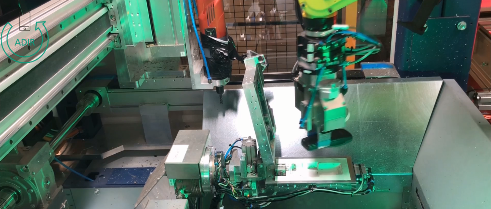 A mobile phone gripped by a robot is loaded into a clamping unit for the disassembly of the MPH in machine 2.